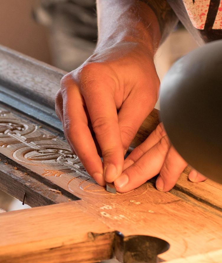Close-up of a craftsman carving detailed patterns into custom wood