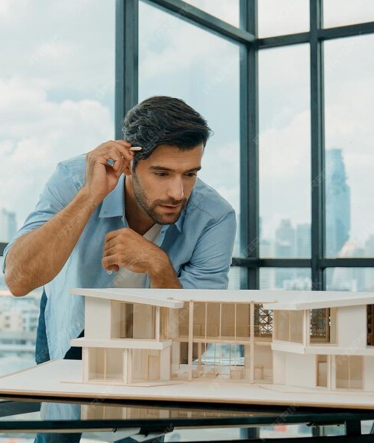 Young male designer studying a wooden architectural building model in a modern office